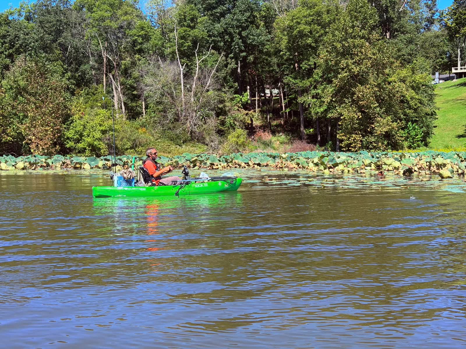 Angler fishing from a bright green kayak beside lily pads at Rocky Fork Lake